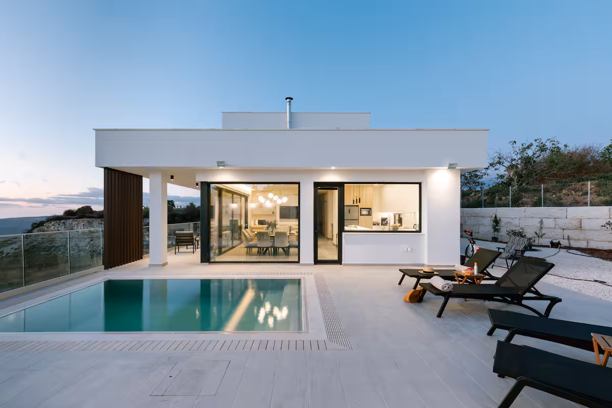 Stella Fyti Heights at dusk with the overflow swimming pool, sun loungers and the glass-fronted living area