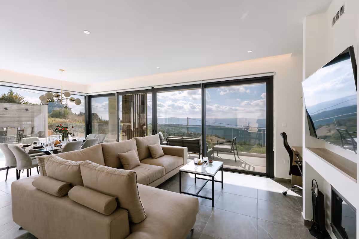 Living room with a large sofa and floor-to-ceiling sliding doors opening onto the terrace and the hills beyond