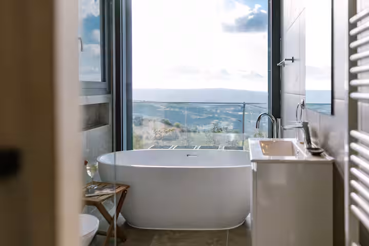 Bathroom with a freestanding bathtub and a window overlooking the hills